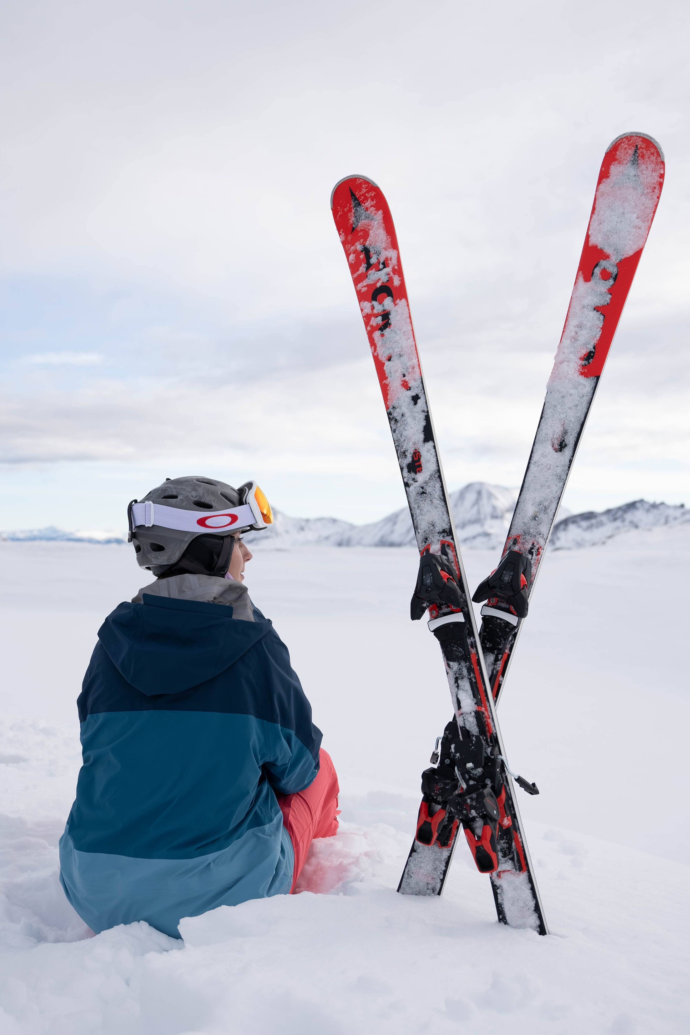 Person sitzt im Schnee neben ihren Skiern